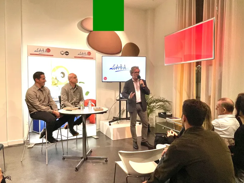 Última mesa redonda de las Jornadas de Arquitectura y Diseño de Lara: un ponente habla de pie junto a dos ponentes sentados