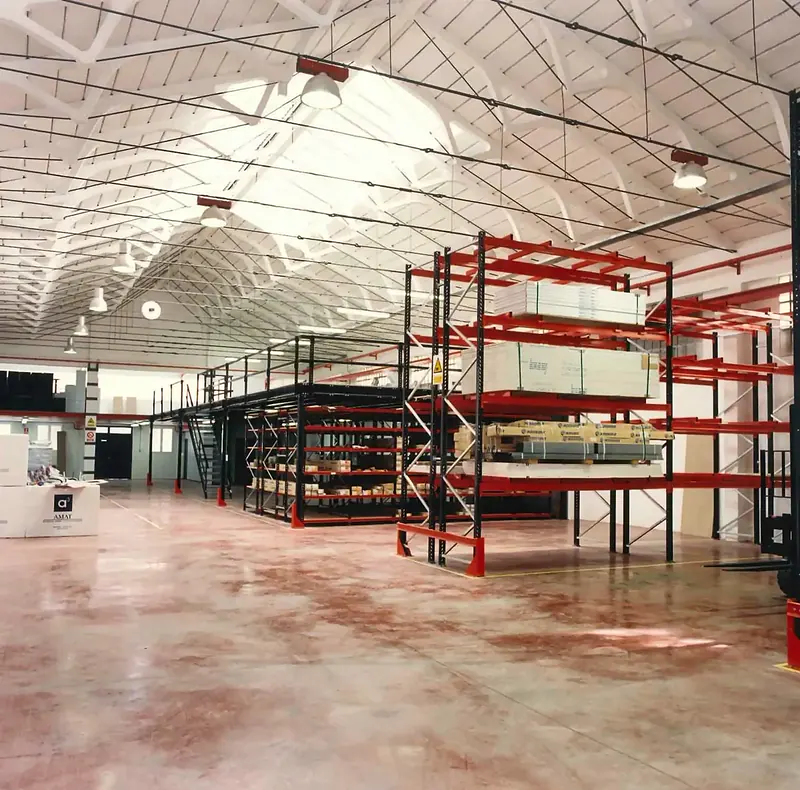 Estanterías rojas de gran altura con mobiliario paletizado bajo la cubierta abovedada del almacén de Lara