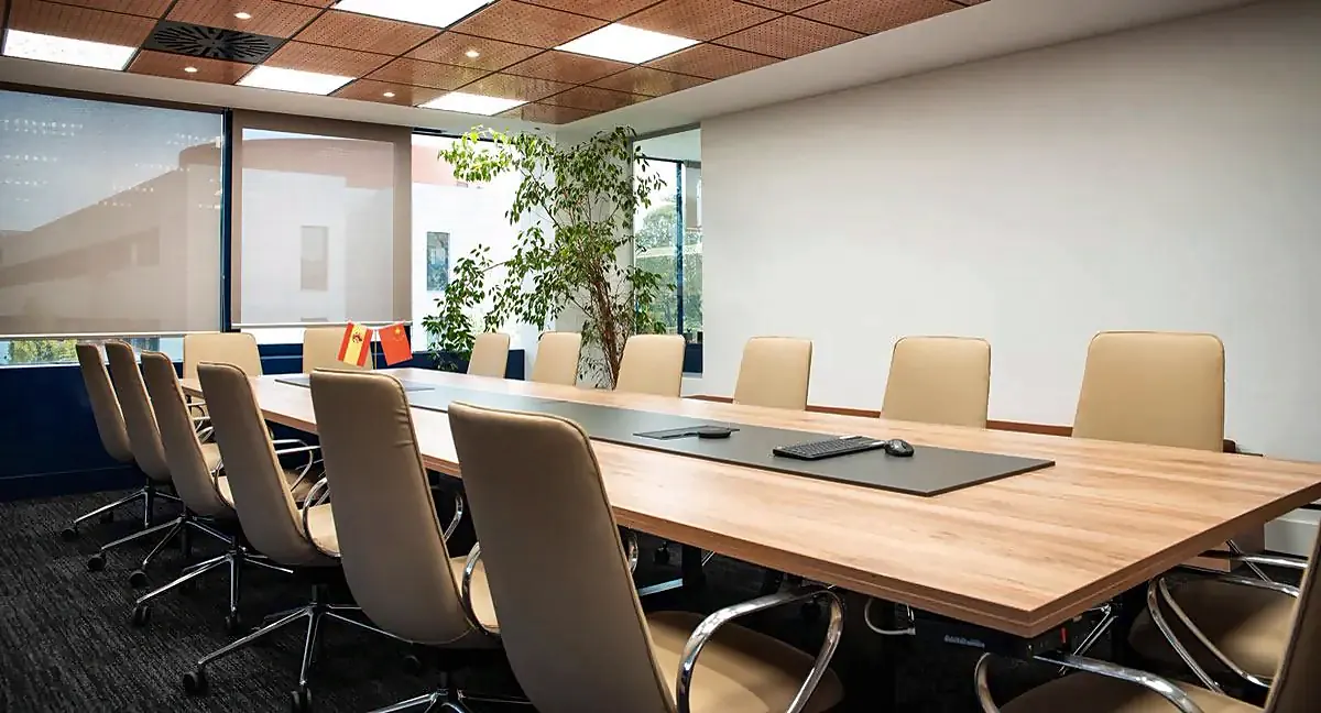 Sala de juntas con mesa larga de madera y sillas tapizadas en beige