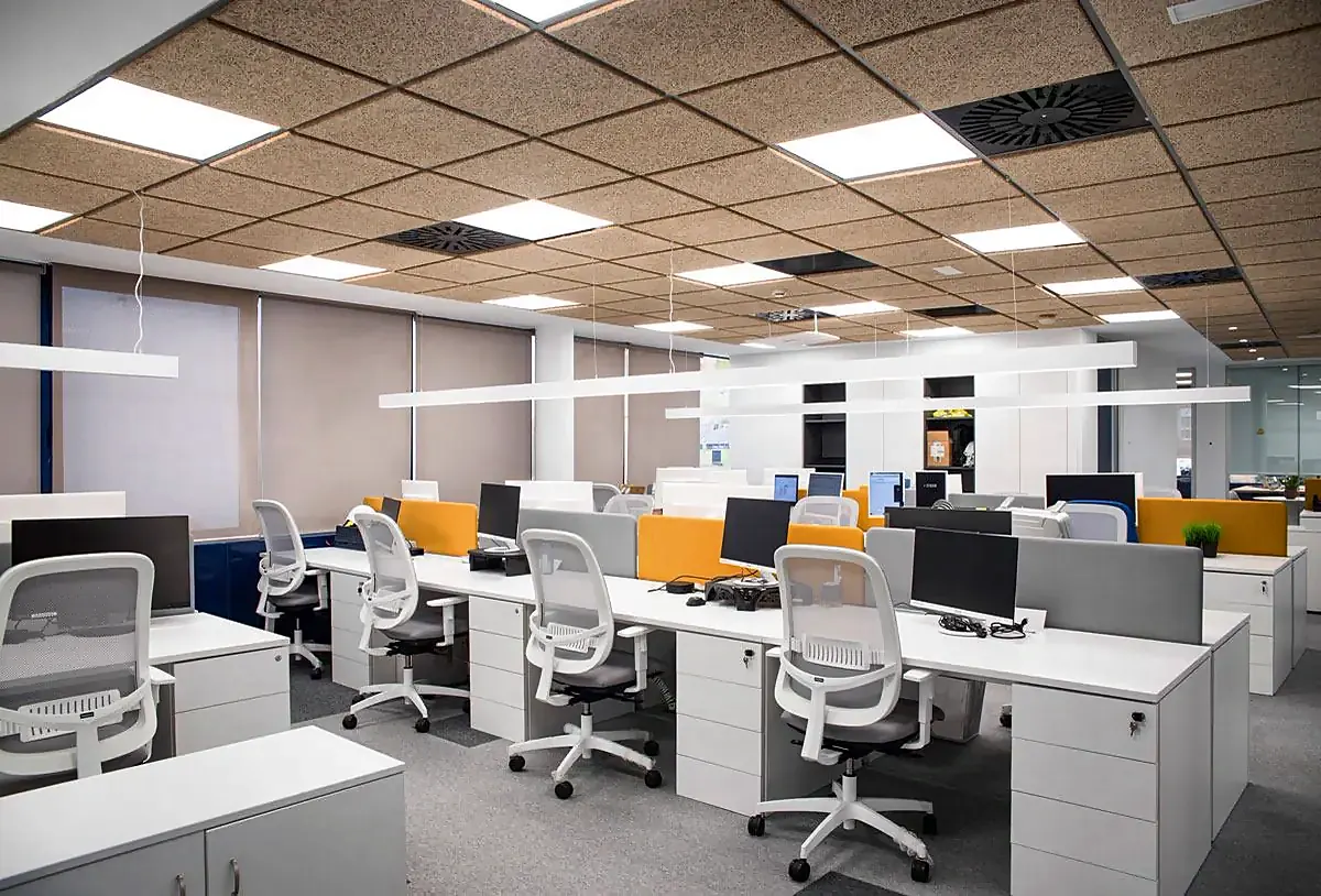 Zona de puestos de trabajo de la sede de Chint en Madrid, con mesas blancas, sillas operativas y techo acústico