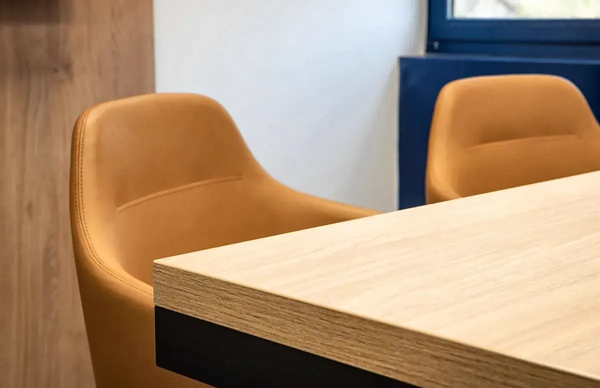 Detalle de butacas tapizadas en naranja junto a una mesa de madera