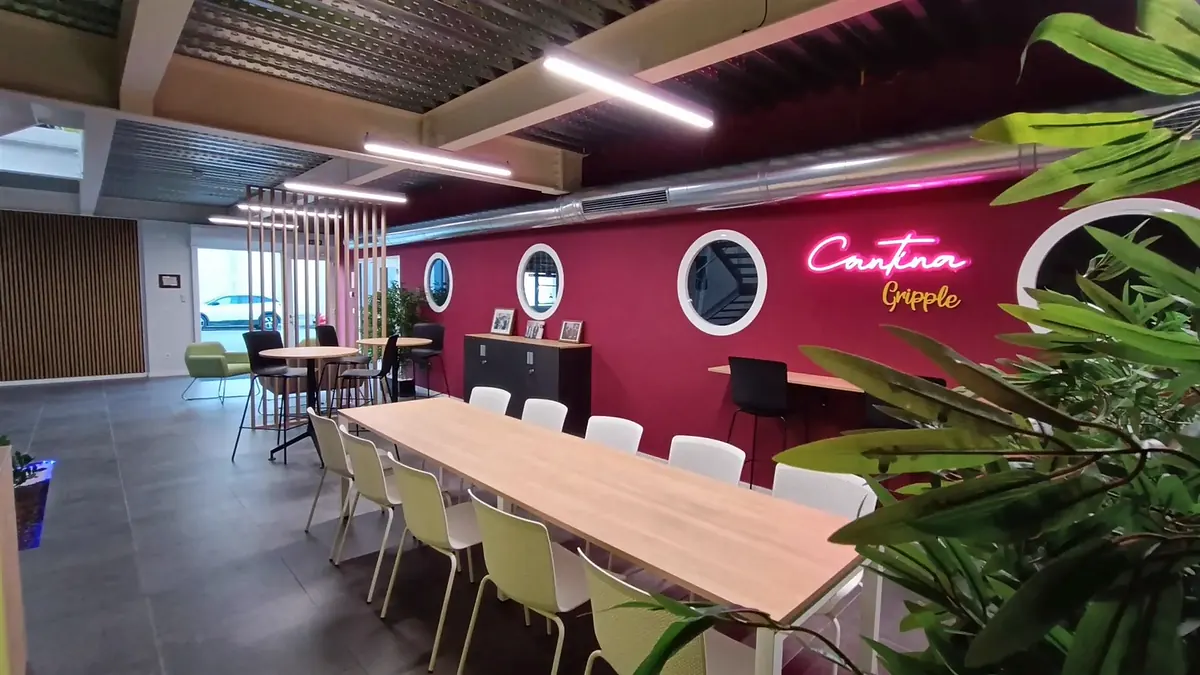 Cantina de Gripple con pared granate, ojos de buey, gran mesa común y celosía de madera